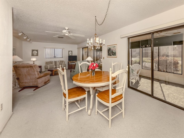 carpeted dining space with ceiling fan with notable chandelier and a textured ceiling