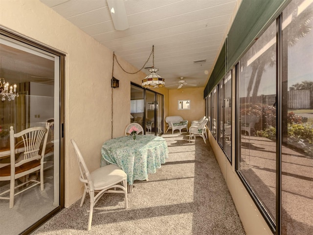 sunroom / solarium featuring ceiling fan with notable chandelier