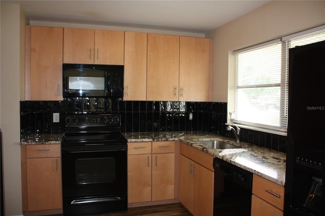 kitchen featuring light stone countertops, decorative backsplash, sink, and black appliances