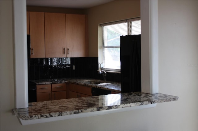 kitchen featuring dark stone countertops, decorative backsplash, and sink