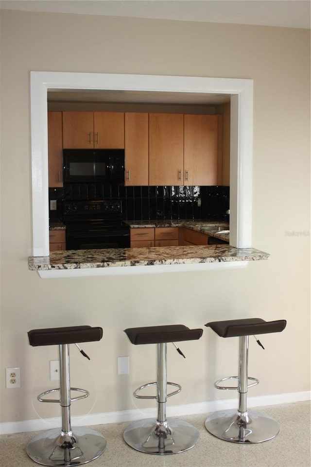 bar with black appliances, dark stone countertops, and tasteful backsplash