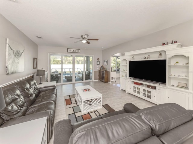 living room featuring a textured ceiling, light wood-type flooring, and ceiling fan