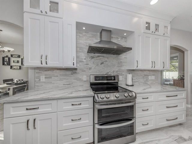 kitchen featuring light stone counters, white cabinetry, wall chimney exhaust hood, and electric stove