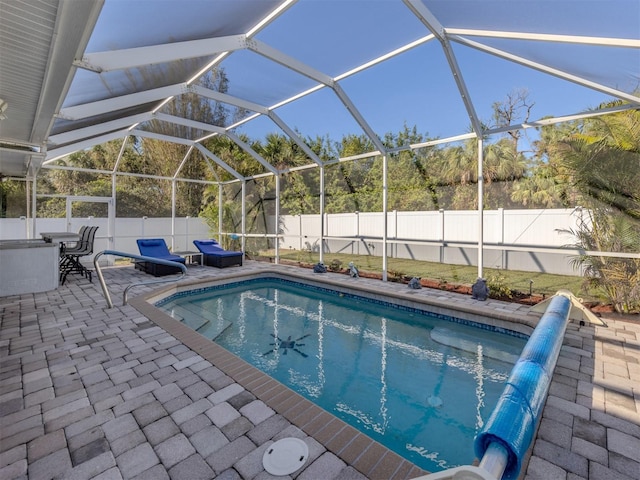 view of pool with glass enclosure and a patio