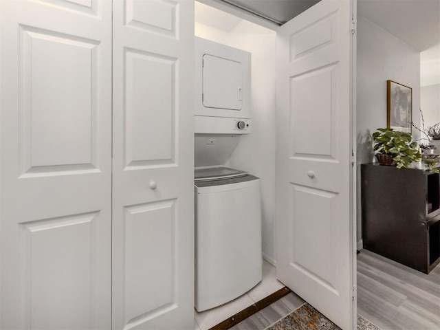 laundry room with stacked washer / drying machine and light wood-type flooring