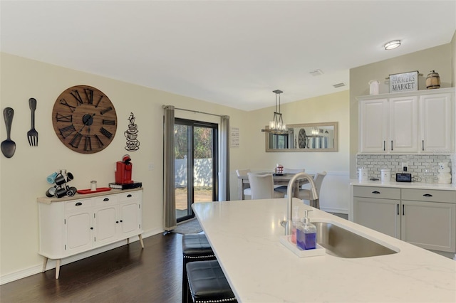 kitchen with dark hardwood / wood-style flooring, tasteful backsplash, sink, white cabinets, and hanging light fixtures