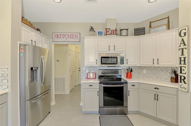 kitchen with appliances with stainless steel finishes, tasteful backsplash, and white cabinetry