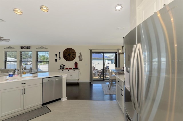 kitchen with appliances with stainless steel finishes, white cabinetry, plenty of natural light, and sink