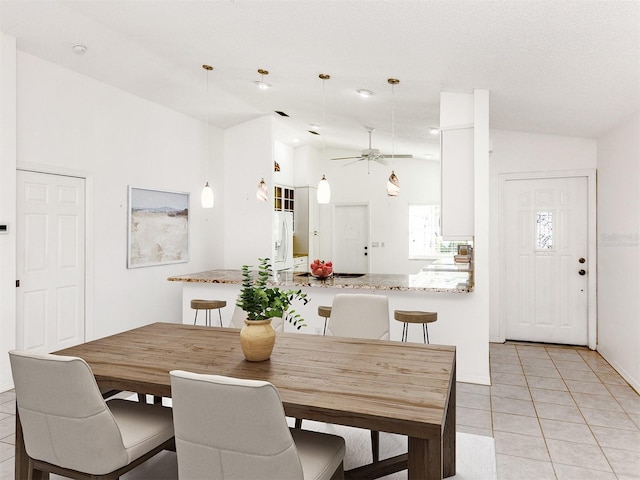 tiled dining room with ceiling fan and lofted ceiling