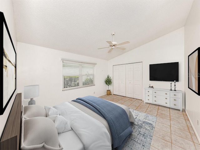 bedroom featuring vaulted ceiling, ceiling fan, light tile patterned floors, a textured ceiling, and a closet