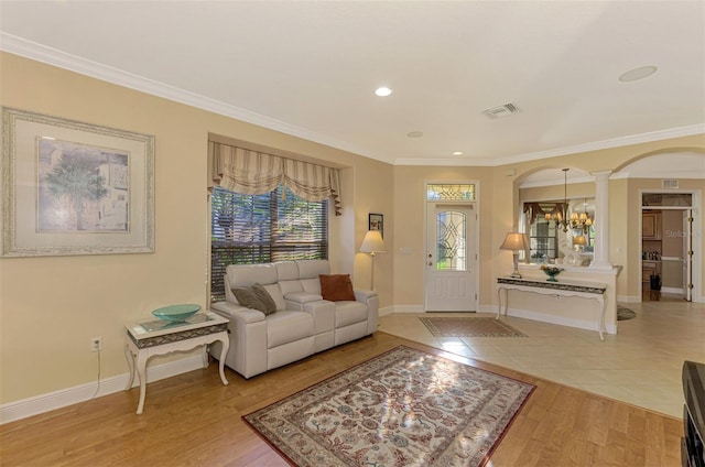 living room featuring decorative columns, light hardwood / wood-style flooring, and ornamental molding