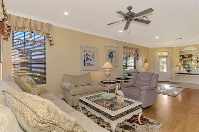 living room featuring ornamental molding, ceiling fan with notable chandelier, and hardwood / wood-style flooring