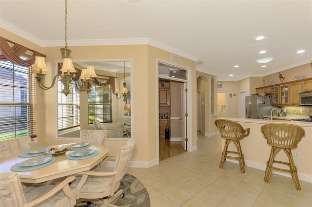 dining space featuring sink, light tile patterned floors, crown molding, and an inviting chandelier