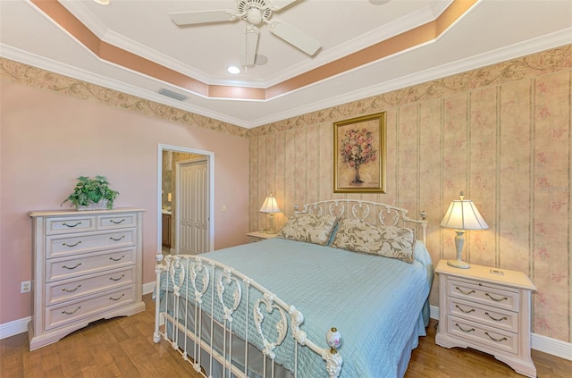 bedroom featuring ceiling fan, light hardwood / wood-style floors, a raised ceiling, and ornamental molding