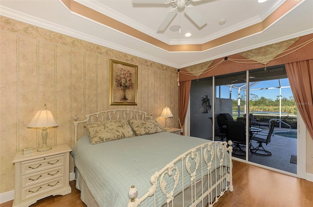 bedroom with ornamental molding, access to outside, a raised ceiling, ceiling fan, and hardwood / wood-style flooring