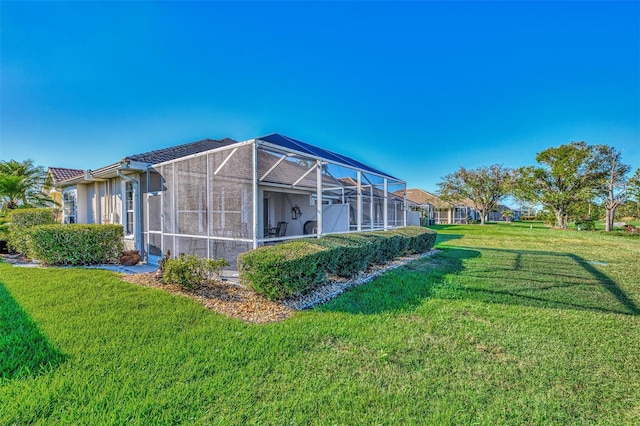 view of side of home featuring a lawn and a lanai