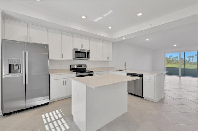 kitchen featuring sink, a kitchen island, kitchen peninsula, white cabinets, and appliances with stainless steel finishes