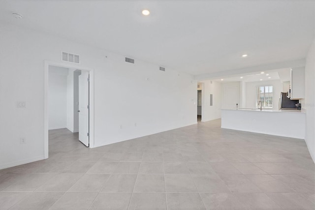 unfurnished living room with light tile patterned floors and sink