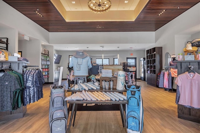 interior space featuring a raised ceiling, light hardwood / wood-style flooring, a towering ceiling, and a chandelier