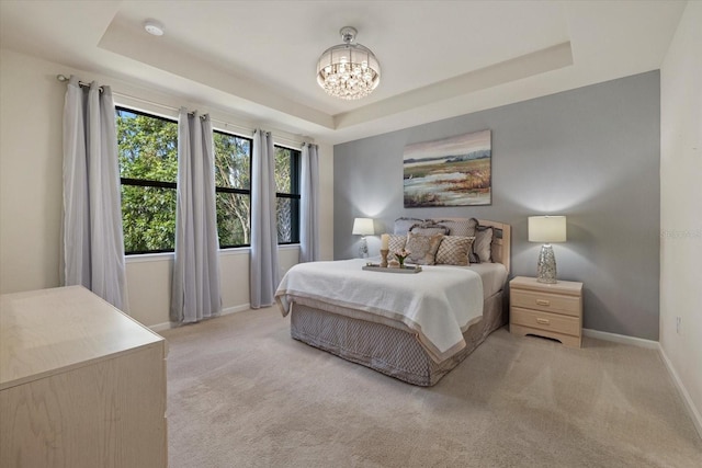 bedroom featuring a raised ceiling, a chandelier, and light colored carpet