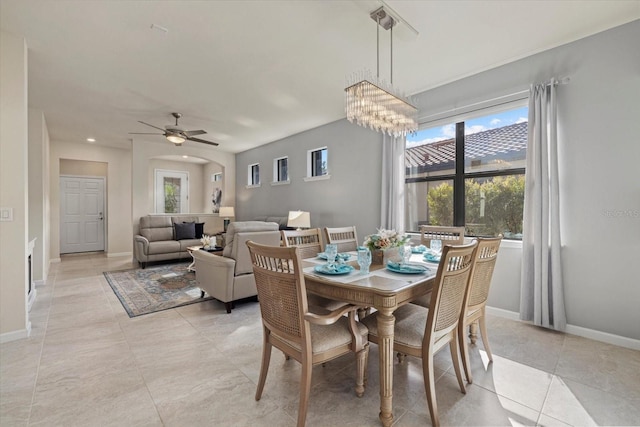 dining area featuring ceiling fan with notable chandelier and light tile patterned flooring