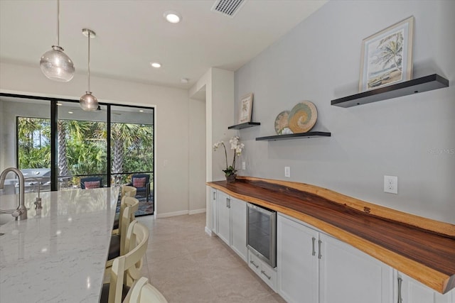 kitchen featuring decorative light fixtures, white cabinetry, butcher block counters, and light tile patterned flooring