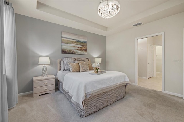 bedroom featuring light carpet, a chandelier, and a tray ceiling