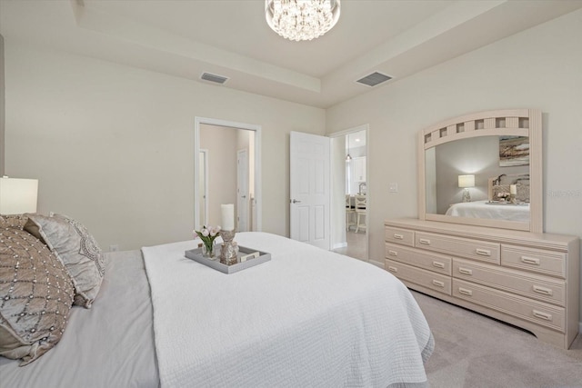 carpeted bedroom featuring a notable chandelier and a tray ceiling