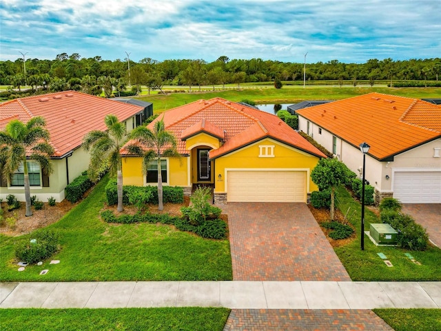 view of front of house featuring stucco siding, a front lawn, a tile roof, decorative driveway, and an attached garage