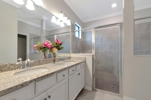 full bath with tile patterned floors, ornamental molding, a shower stall, and a sink