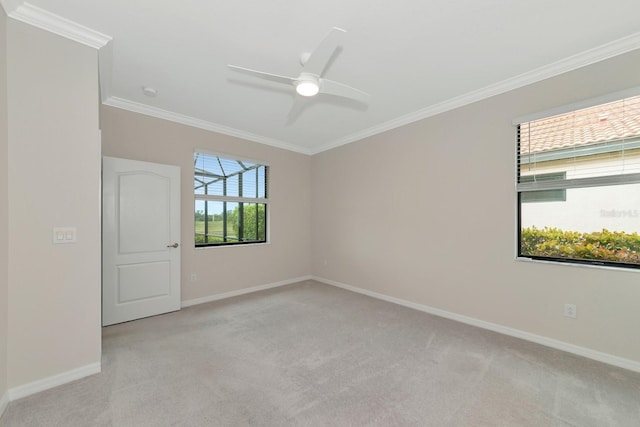 spare room featuring a ceiling fan, crown molding, light colored carpet, and baseboards