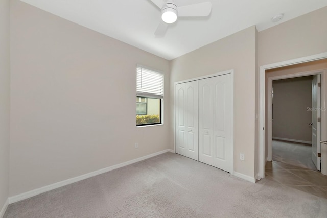 unfurnished bedroom with a closet, light carpet, and baseboards