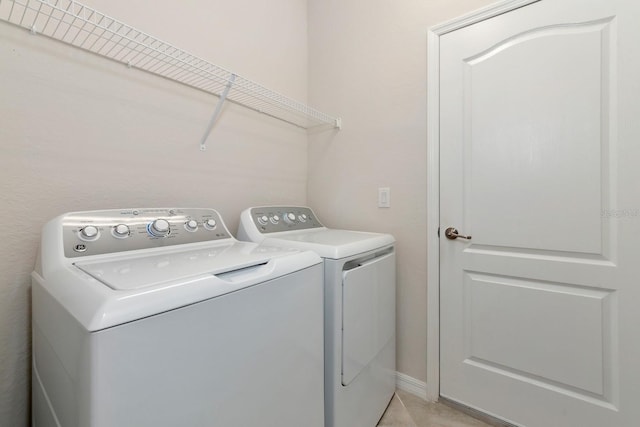 laundry area with washing machine and clothes dryer, laundry area, and light tile patterned floors