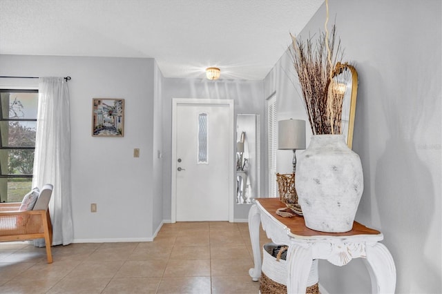 entrance foyer with light tile patterned floors, a textured ceiling, and a wealth of natural light