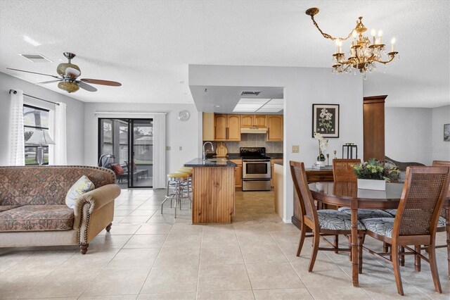 dining room with sink, a textured ceiling, ceiling fan with notable chandelier, and light tile patterned flooring