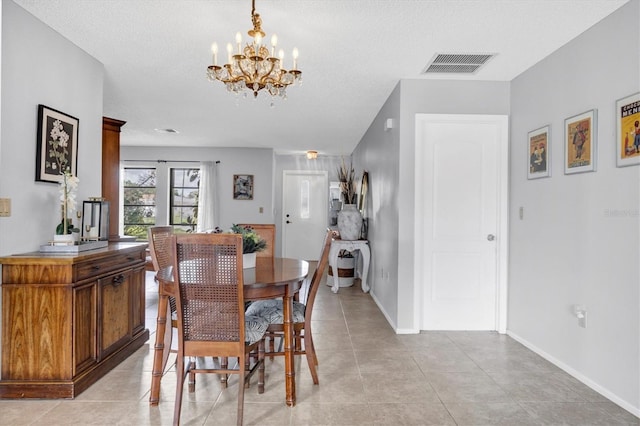 tiled dining area with a textured ceiling and an inviting chandelier