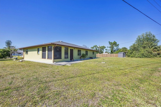 back of house with a storage unit and a lawn