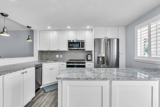 kitchen featuring sink, hanging light fixtures, light hardwood / wood-style floors, white cabinetry, and stainless steel appliances