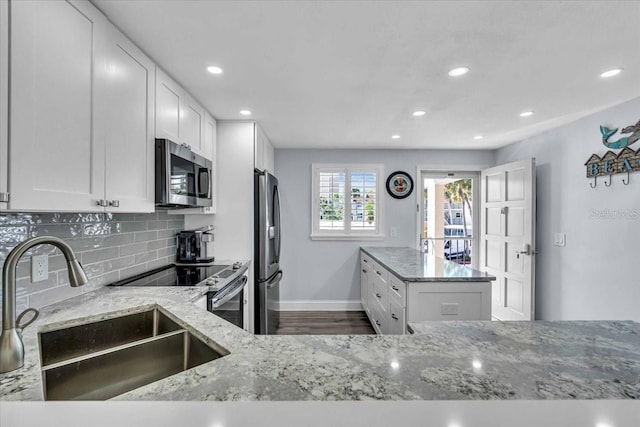 kitchen with light stone countertops, sink, dark wood-type flooring, stainless steel appliances, and white cabinets