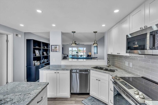 kitchen with white cabinets, sink, light stone countertops, and stainless steel appliances