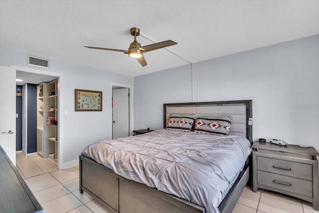 bedroom featuring light tile patterned floors, a textured ceiling, ensuite bathroom, and ceiling fan