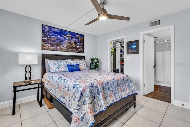 tiled bedroom featuring a spacious closet, a closet, and ceiling fan