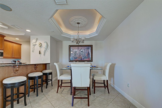 tiled dining space featuring a chandelier, a textured ceiling, and a tray ceiling