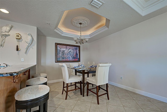 dining space featuring a raised ceiling, light tile patterned floors, a chandelier, and a textured ceiling