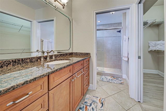 bathroom featuring a tile shower, tile patterned floors, vanity, and toilet