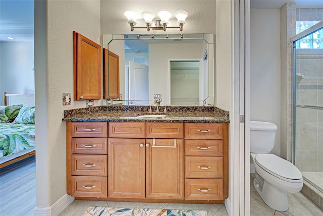 bathroom featuring tile patterned flooring, vanity, toilet, and a shower with door