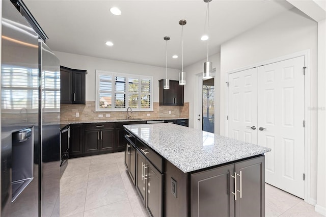 kitchen with a center island, sink, hanging light fixtures, stainless steel fridge with ice dispenser, and backsplash