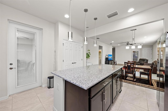 kitchen with decorative light fixtures, ceiling fan, a kitchen island, and dark brown cabinetry