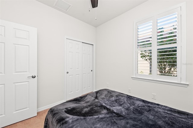 carpeted bedroom with multiple windows, ceiling fan, and a closet