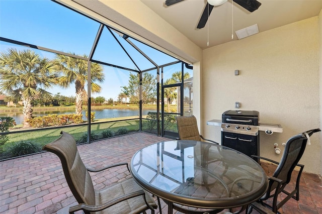 sunroom with ceiling fan and a water view